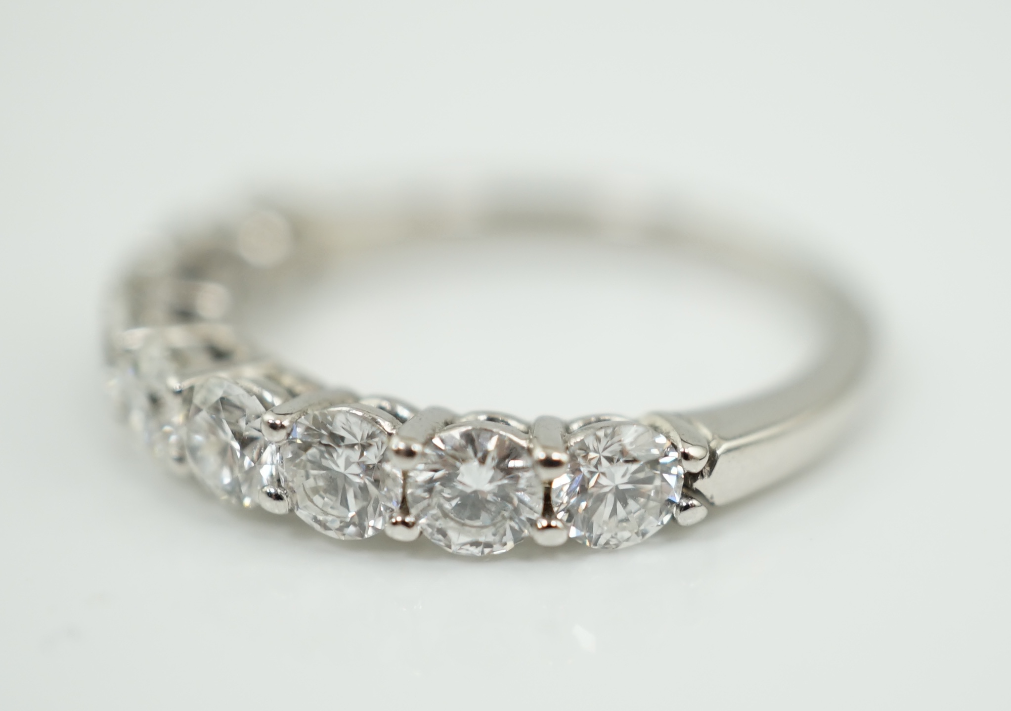 A white gold and nine stone set round brilliant cut diamond set half hoop ring